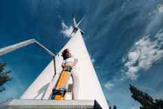 女孩白色衣服眼镜滑冰手拍摄大风涡轮机场树现代女人骑董事会场风车