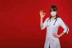 年轻的医生白色外套站红色的背景显示手标志细医生显示订单孤立的
