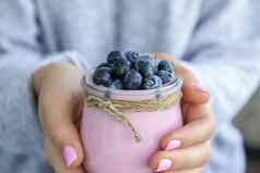 女手持有碗酸奶蓝莓表格女人吃蓝莓酸奶新鲜的蓝莓健康的早餐超级食物健康的吃素食者素食主义者食物