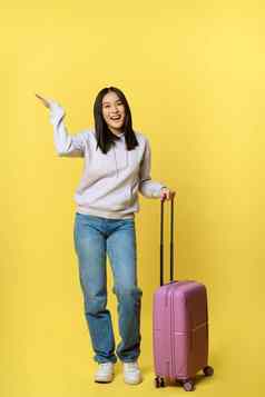 完整的长度拍摄快乐亚洲女孩假期旅游手提箱微笑乐观的站黄色的背景