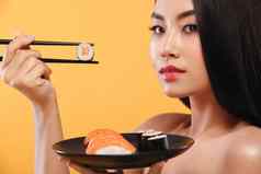 特写镜头肖像亚洲女人吃寿司卷黄色的背景