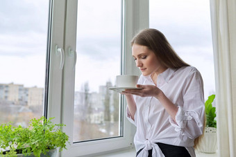 年轻的美丽的女人杯茶首页窗口