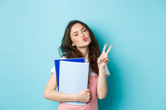 肖像魅力女孩显示接吻脸地摆携带笔记本电脑家庭作业材料站蓝色的背景