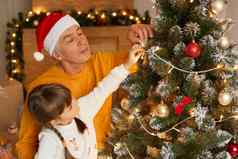 祖父（外）孙女装修冷杉树圣诞节夏娃集中圣诞节树穿休闲的衣服摆姿势节日生活房间感觉快乐花时间