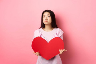 情人节概念孤独的十几岁的亚洲女孩做梦爱感觉伤心孤独的情人一天遗憾持有<strong>大</strong>红色的心粉红色的背景