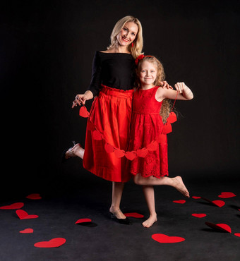 妈妈。女儿持有花环红色的情人节心快乐情人节地板上心美丽的婚礼2月假期情感永远订婚红色的衣服女孩光着脚