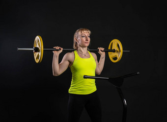 女孩健身蹦床黑色的背景黄色的t恤黑色的健身房女人有趣的身体<strong>健康</strong>飞跃重量俱乐部<strong>健康</strong>有氧<strong>运动运动</strong>肌肉教练享受