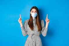 人科维德检疫概念感兴趣年轻的女人指出广告站衣服脸面具冠状病毒蓝色的背景