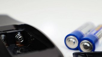 黑色的远程控制蓝色的aaa电池白色背景电池更换备用部分电池空室远程控制特写镜头