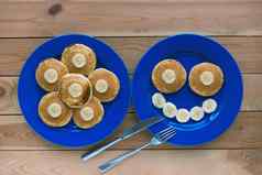 煎饼微笑蓝色的板木背景香蕉水果微笑早餐有趣的食物孩子们