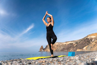 年轻的女人长头发健身教练黑色的运动服装<strong>紧身</strong>裤<strong>上衣</strong>伸展运动普拉提瑜伽席海阳光明媚的一天女健身瑜伽例程概念
