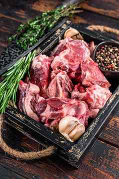 生羊肉山羊肉丁炖肉骨黑暗木背景前视图