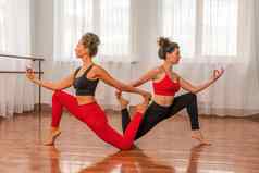 年轻的女士健身教练红色的运动服装紧身裤前伸展运动健身房普拉提瑜伽席大窗口阳光明媚的一天女健身瑜伽例程概念