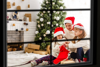 年轻的大家庭庆祝圣诞节享受晚餐视图窗口装饰生活房间树蜡烛灯快乐父母吃孩子们