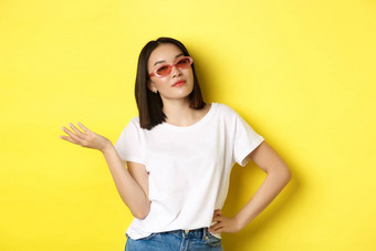 时尚生活方式概念时髦的自信亚洲女人时尚的太阳镜自信的相机站黄色的背景