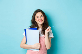 美丽的女孩学生深思熟虑的前复制空间站笔记本电脑家庭作业微笑沉思的站蓝色的背景