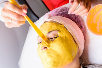 水疗中心治疗美沙龙手<strong>专业美容师</strong>应用黄金面具客户的脸