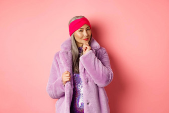 时尚<strong>购</strong>物概念时尚的亚洲夫人<strong>紫色</strong>的人造革外套感兴趣感兴趣促销活动微笑思考粉红色的背景