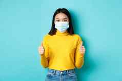 科维德社会距离流感大流行概念支持亚洲女人推荐促销活动穿医疗面具显示拇指站蓝色的背景