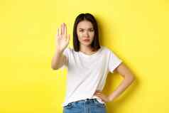 自信亚洲女人显示停止手势禁止警告不同意站心烦意乱黄色的背景