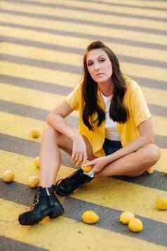 女孩柠檬黄色的衬衫短裤黑色的鞋子坐在黄色的行人穿越城市柠檬情绪