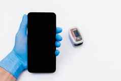 手医疗医生乳胶橡胶手套持有移动电话智能手机屏幕背景脉冲血氧计