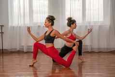 年轻的女士健身教练红色的运动服装紧身裤前伸展运动健身房普拉提瑜伽席大窗口阳光明媚的一天女健身瑜伽例程概念