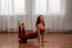 年轻的女人健身教练红色的运动服装紧身裤前伸展运动健身房普拉提瑜伽席大窗口阳光明媚的一天女健身瑜伽例程概念