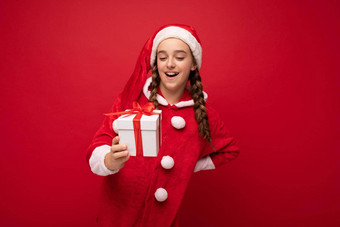 拍摄有吸引力的快乐微笑浅黑肤色的女人女孩孤立的红色的背景墙穿圣诞老人老人西装持有白色礼物盒子红色的丝带惊喜