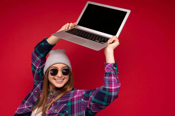 特写镜头照片令人惊异的迷人的美丽的笑有趣的微笑年轻的女人持有电脑移动PC空监控屏幕穿太阳眼镜他色彩鲜艳的衬衫一边孤立的红色的背景