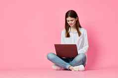 女人移动PC坐着地板上互联网沟通在线粉红色的背景