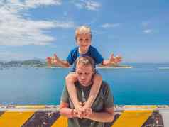 前面男孩儿子笑坐着父亲肩膀Photoshop太阳皮肤海云岛背景有趣的照片幸福生活方式父亲的一天爱为人父母家庭假期概念