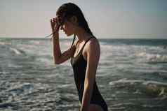 女人黑色的泳衣走海滩海洋夏天