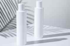 白色塑料护肤品管背景热带植物影子