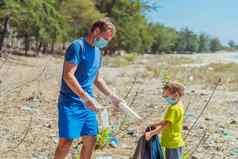 志愿者蓝色的脸面具森林沙子海滩儿子帮助父亲持有黑色的袋选择垃圾问题泄漏垃圾垃圾地球污染环境保护自然孩子们教育