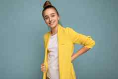 照片拍摄迷人的积极的快乐微笑浅黑肤色的女人女少年穿时尚的黄色的夹克白色t恤站孤立的蓝色的背景墙相机