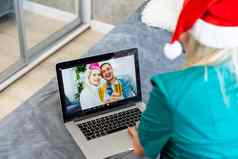 微笑女孩穿圣诞老人他视频调用家庭网络摄像头女人移动PC坐着厨房首页虚拟会议闲谈，聊天假期快乐圣诞节一年正常的