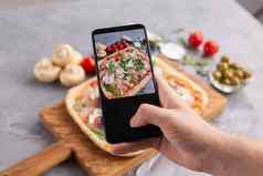 老板需要图片煮熟的意大利披萨帕尔马他智能手机拍摄食物社会网络概念