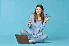 女人移动PC坐地板上学习互联网技术蓝色的背景