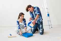 改造重新装饰内饰概念年轻的夫妇坐着白色地板上对于油漆