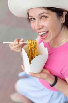 特写镜头年轻的女人他吃中国人面条走公园温暖的夏天一天外卖食物概念