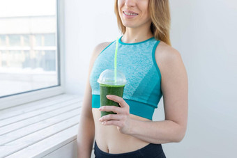 健康的健身排毒概念关闭年轻的女人体育穿绿色奶昔微笑在室内
