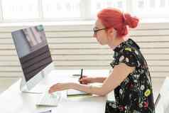 图形设计师动画师插画家概念年轻的女人红色的头发工作移动PC