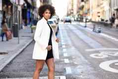 年轻的黑色的女人非洲式发型发型站城市背景