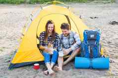 宠物夏天旅游自然概念年轻的夫妇坐着猫帐篷