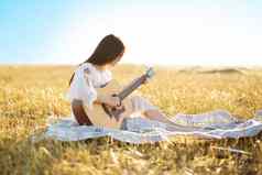 夏天伟大的梦想时间美丽的女孩玩吉他小麦场