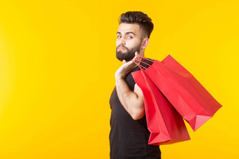 男人。持有红色的购物袋黄色的背景概念购物超市礼物广告空间