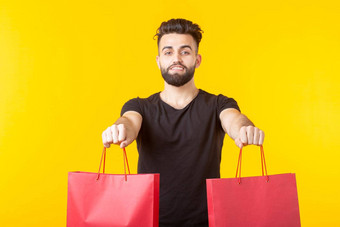 男人。持有红色的购物袋黄色的背景概念购物超市礼物广告空间