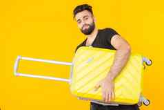 可爱的漂亮的年轻的阿拉伯男人。胡子持有黄色的手提箱手黄色的背景概念旅行假期