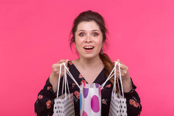 积极的年轻的时尚的女人持有袋摆姿势粉红色的背景购物概念购物中心